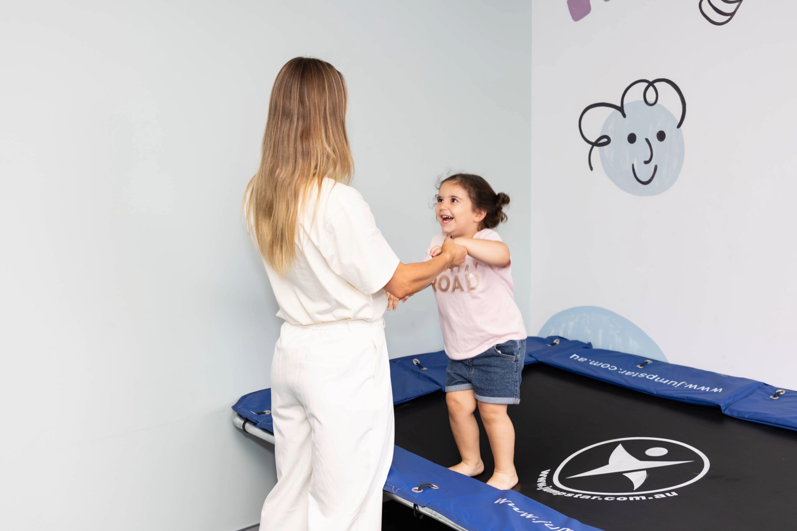Child walking on balance beam supported by therapist